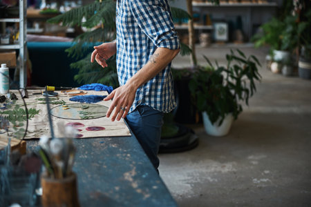 Male herbalist in plaid shirt making herbarium in workshopの写真素材