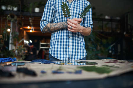 Young man in plaid shirt holding green plants