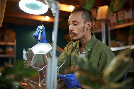 Handsome young man making glass florarium in workshopの写真素材