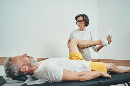 Focused osteopathic physician examining a calm mature patientの写真素材