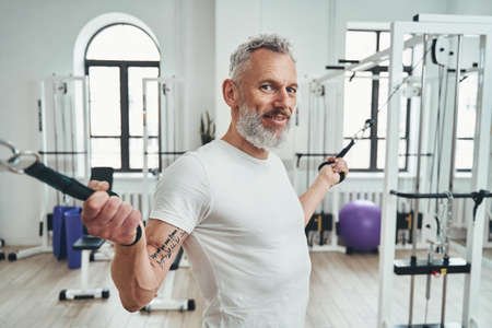 Sportsman with cable machine handles in his hands looking ahead