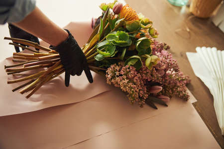 Qualified florist wrapping a bouquet on the table