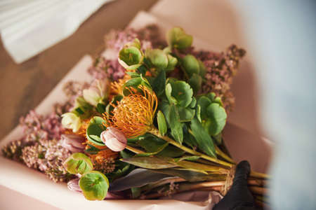 Gloved hand placing a gorgeous bouquet on the craft paperの写真素材