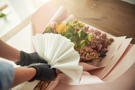Woman in nitrile gloves wrapping a bouquet of mixed flowersの写真素材