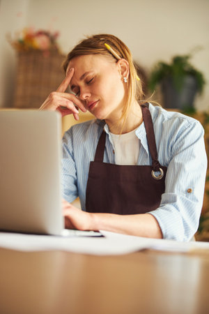 Tired professional floral arranger dozing before her laptopの写真素材