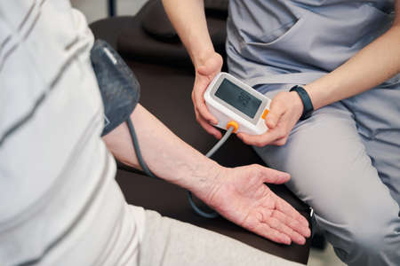 Medical worker using blood pressure monitor on pensioner
