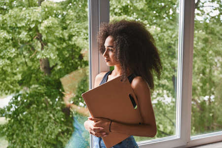 Calm woman with folder standing alone indoors