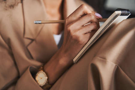 Hand of woman with watch on wrist holding pencil