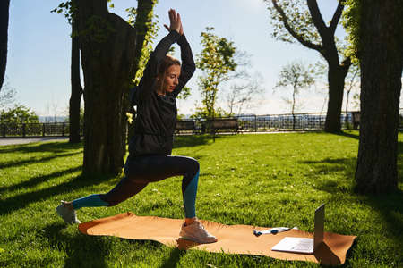 Serene woman doing yoga with laptop outdoors