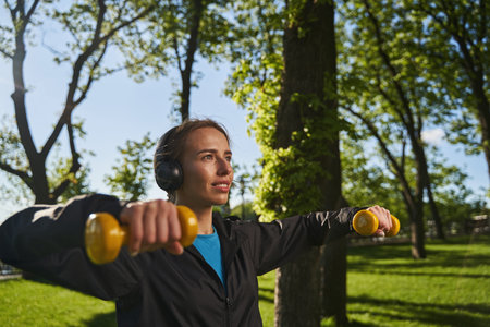 Happy female exercising arms with equipment outdoorsの写真素材