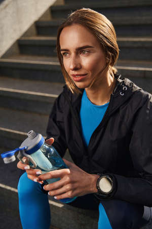 Happy female in sportswear with bottle of water