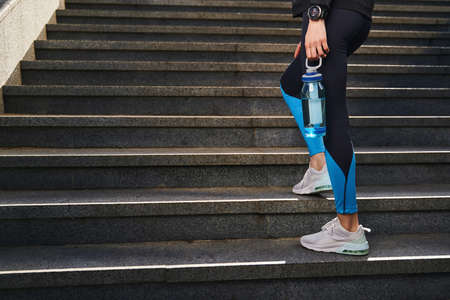 Slim fit woman with drink walking in city