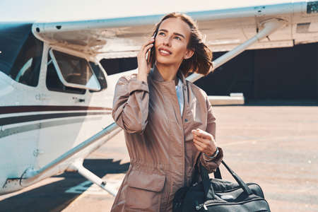Beautiful young woman talking on cellphone at airportの写真素材