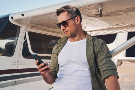 Handsome young man using mobile phone at airportの写真素材