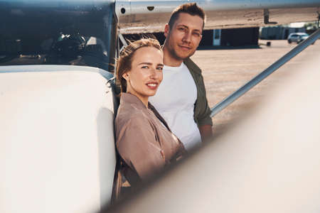 Beautiful couple standing by aircraft at airfieldの写真素材