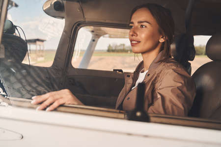 Beautiful young woman sitting inside airplane cockpitの写真素材