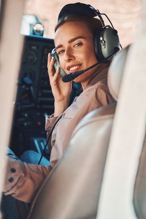 Cheerful young woman sitting in aircraft pilot cabin