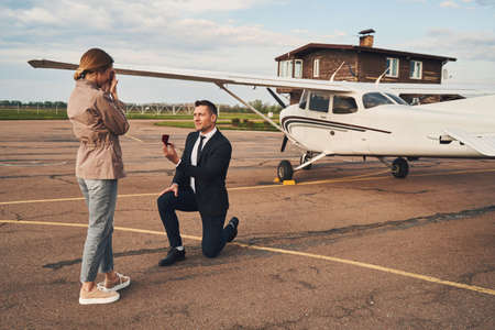 Handsome man making proposal to his girlfriend at airdrome