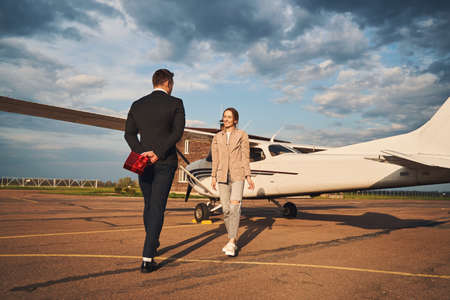 Beautiful couple in love standing near plane at airfieldの写真素材