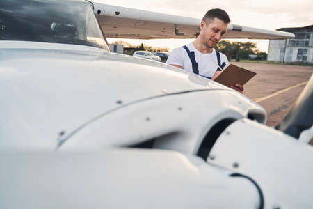 Handsome male worker writing on clipboard at airdromeの写真素材