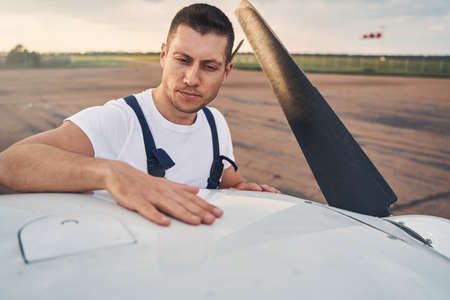 Aircraft mechanic inspecting airplane outdoors at aerodromeの写真素材