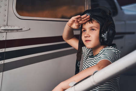 Adorable boy standing by aircraft and salutingの写真素材
