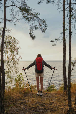 Female standing on riverbank with walking poles