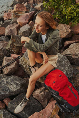 Backpacker during a rest on a rock at riverbankの写真素材