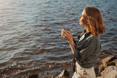 Female standing on shore with tea mugの写真素材
