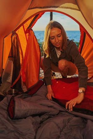 Tourist preparing a sleeping place inside tent