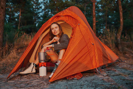 Female dipping spoon into pot with tea during hiking