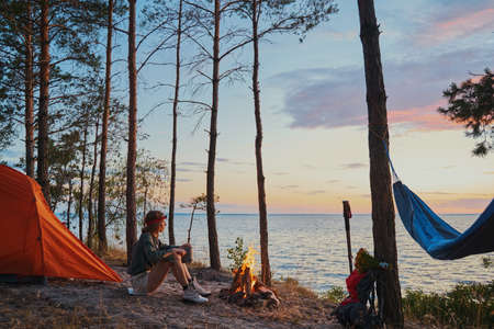 Backpacker warming up near campfire with tea