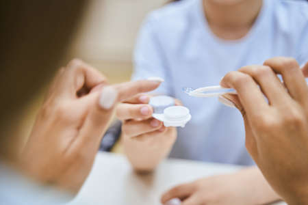 Ophthalmologist showing contact lenses to patient in clinicの写真素材