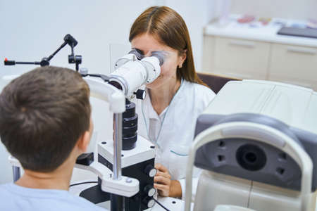 Doctor examining child eyes with ophthalmic equipmentの写真素材