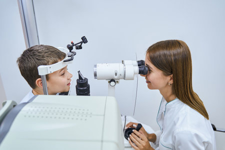 Female doctor examining child eyes with ophthalmic equipment