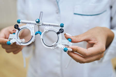 Female doctor hands holding optical trial lens frame