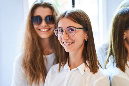 Cheerful young women in glasses standing in optical store