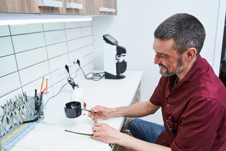 Bearded male optician with glasses working in optical workshop