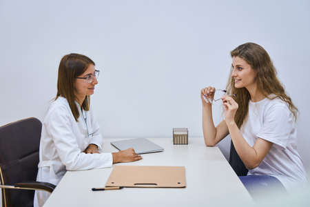 Joyful young woman having appointment with optician in clinicの写真素材
