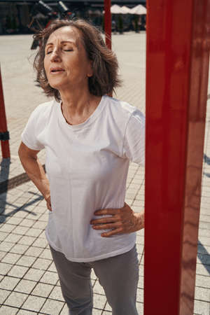 Mature fit woman relaxing after training outdoorsの写真素材