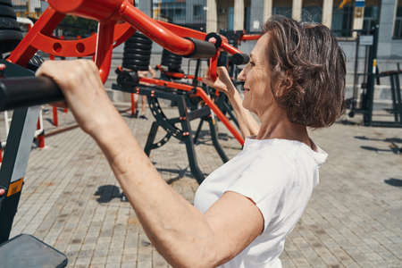 Fit senior woman doing pull us with equipment
