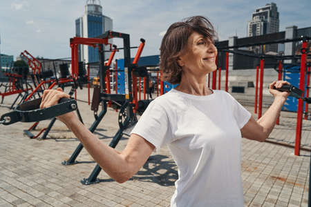 Happy mature female enjoying workout on sports ground