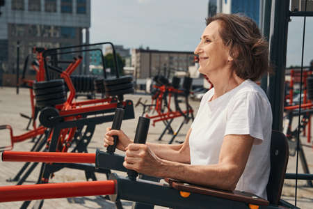 Jolly mature female training core on sports ground