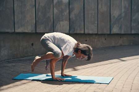 Mature slim woman doing yoga in cityの写真素材