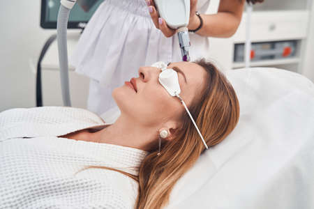Pretty woman enjoying face rejuvenation procedure in clinic