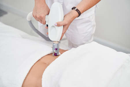 Cosmetologist healing skin on female belly with laserの写真素材