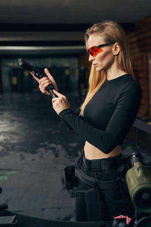 Focused young female shooter concentrated on loading the gunの写真素材
