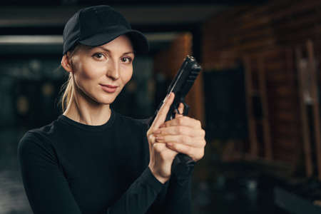 Calm woman with a firearm standing indoors