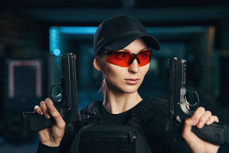 Cute female shooter with two pistols looking awayの写真素材