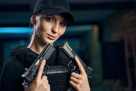 Professional female sniper posing for the camera with her handgunsの写真素材
